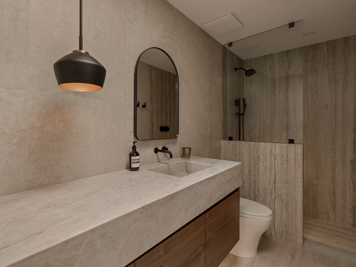 A bathroom with an integrated stone basin, wall-mounted mixer, black shower system and toilet