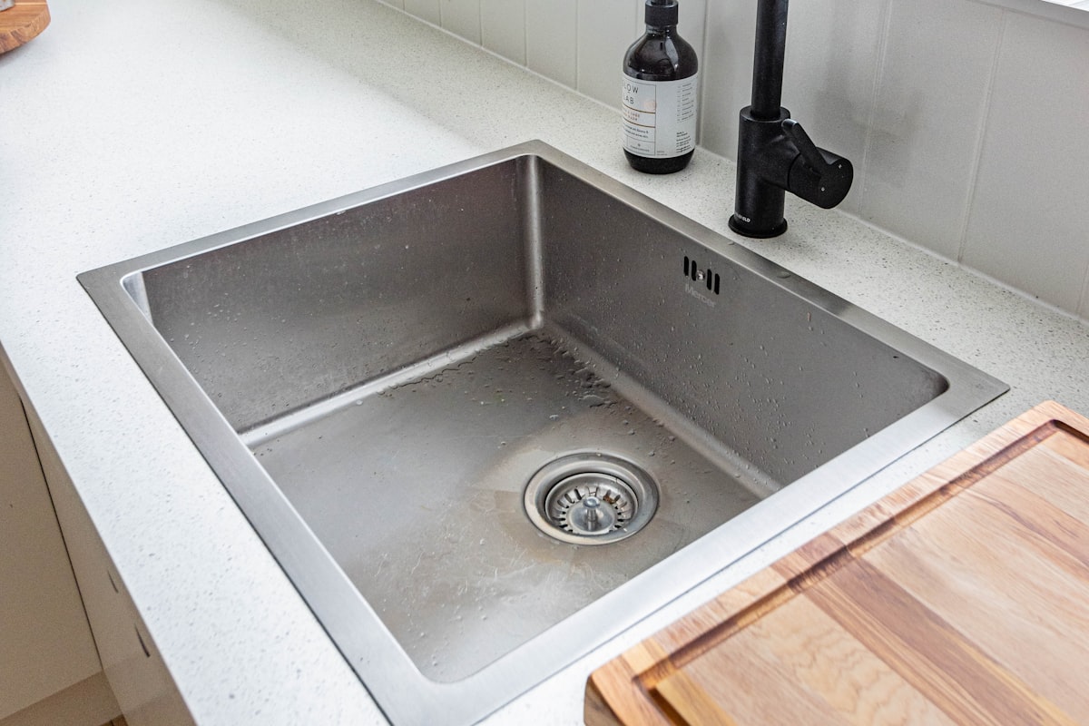 A flush-mount stainless steel single bowl sink with a matte black pull-out mixer