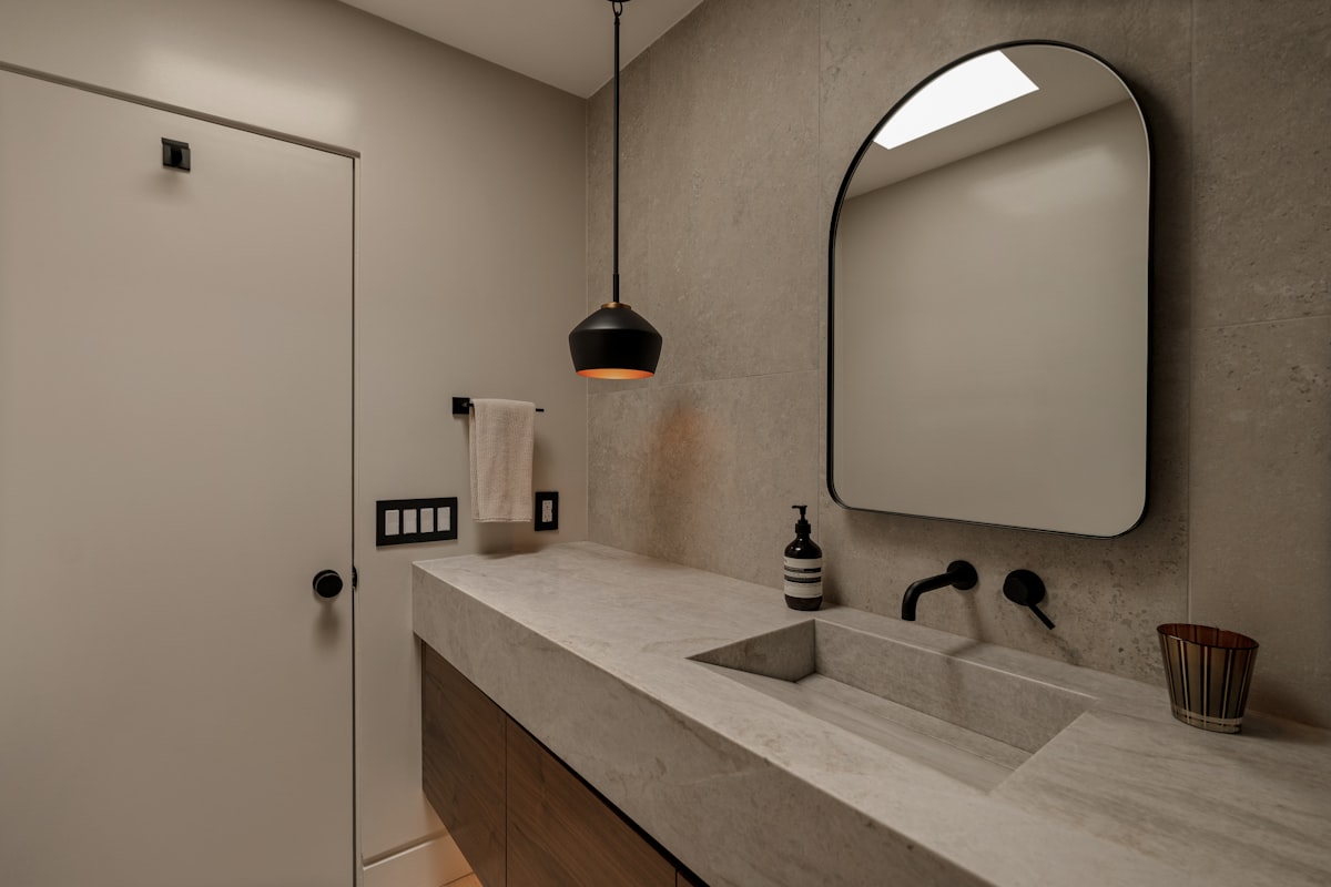 A wall-mounted matte black mixer over an integrated stone basin